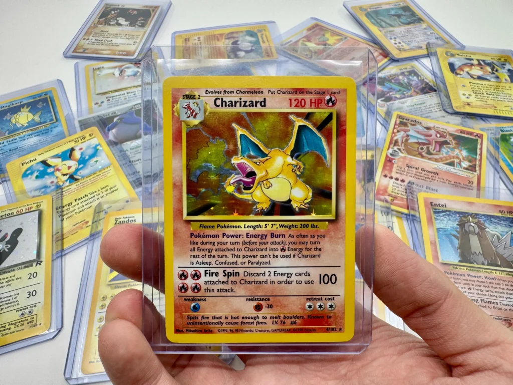 Vintage Base Set Charizard holo Pokémon card held in a top loader with classic vintage Pokémon cards in the background
