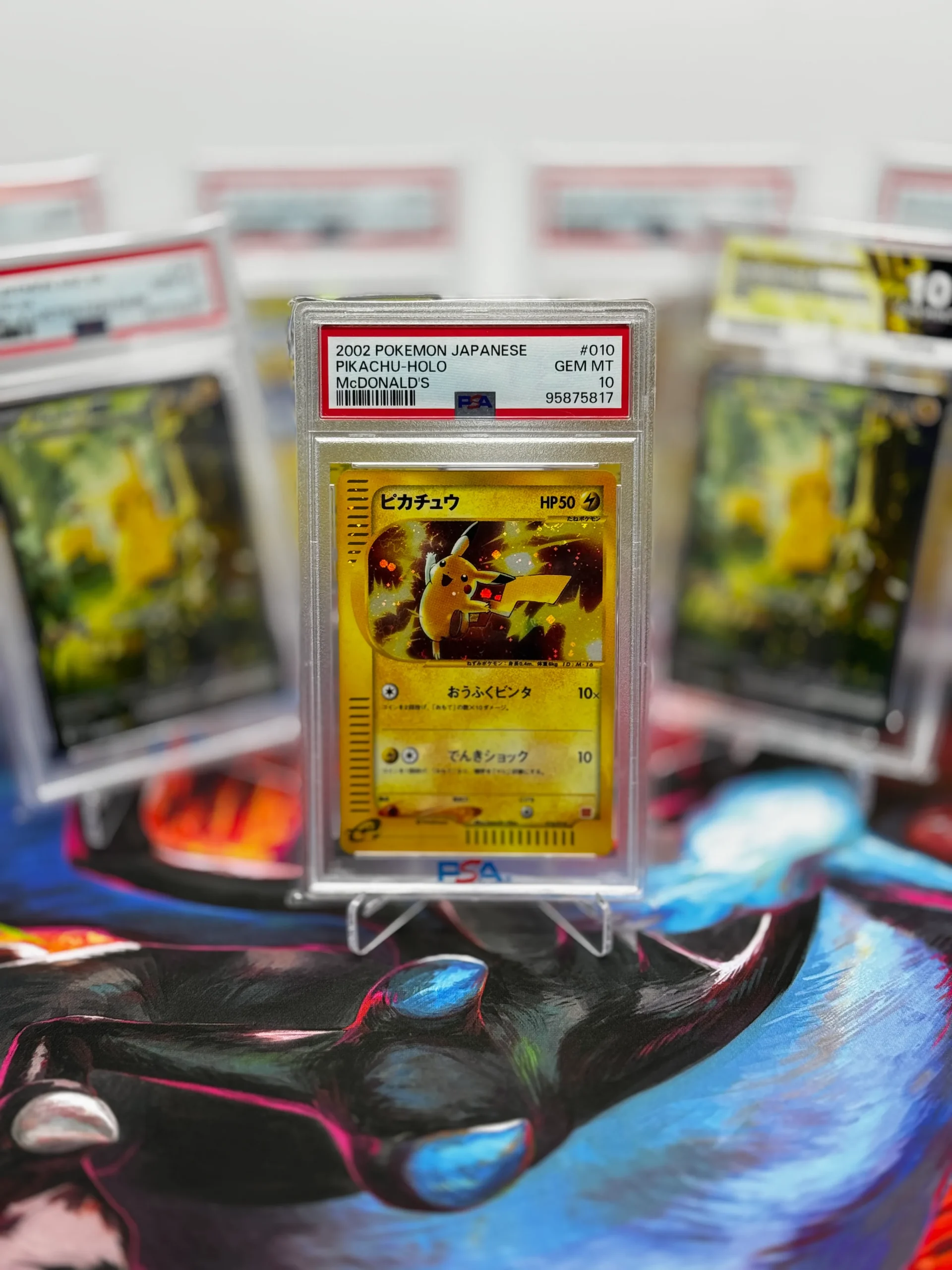 PSA 10 2002 Japanese McDonald’s Pikachu holo Pokémon card displayed in front of other graded Pikachu slabs PSA 10 2002 Japanese McDonald’s Pikachu holo Pokémon card displayed in front of other graded Pikachu slabs